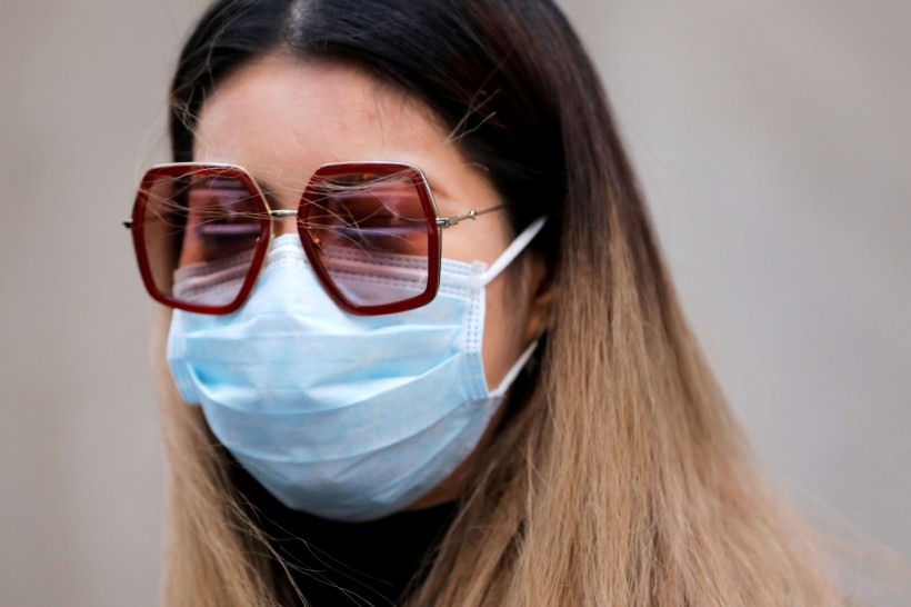 A woman in a face mask walks in the downtown area