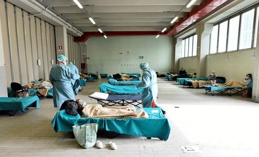 Medical personnel wearing protective face masks help patients inside the Spedali Civili hospital in Brescia, Italy