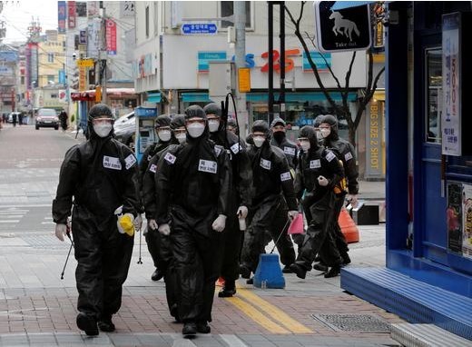South Korean soldiers in protective gear make their way while they disinfect buildings downtown in Daegu, South Korea