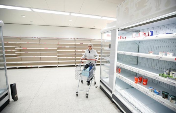 A customer pushes her trolley next to empty shelves at a Sainsbury's store in Harpenden as the spread of the coronavirus disease continues