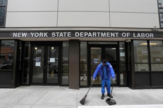 A person sweeps outside the entrance of the New York State Department of Labor offices,