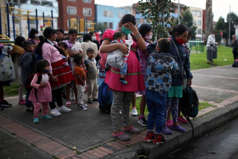 Indigenous people wearing protective face masks as a preventive measure against the spread of the coronavirus disease (COVID-19) carry their belongings after being evicted from a building in Bogota, Colombia.