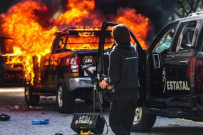 A police officer stands near a burning police vehicle after demonstrators set it on fire during a protest