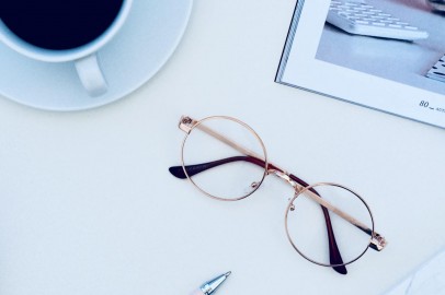 Brown Framed Eyeglasses Near Cup of Coffee on White Surface