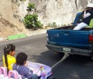 Children in a toy car were photographed being dragged by a 4x4 truck on a highway.