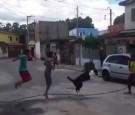 A dog jumps rope with a few children on the street.