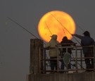 The moon sets behind people fishing on a pier during its closest orbit to the Earth since 1948 on November 14, 2016 in Redondo Beach, California. 