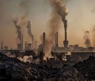 Smoke billows from a large steel plant as a Chinese labourer works at an unauthorized steel factory, foreground, on November 4, 2016 in Inner Mongolia, China.