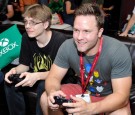 Actor Scott Porter (R) and his brother Brendan Porter take a break from Comic-Con to play the latest titles on Xbox One in the Microsoft VIP Lounge on July 26, 2014 in San Diego, California.