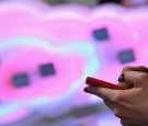 A visitor tries out a Microsoft-driven Nokia smartphone next to a symbol of a cloud at the Deutsche Telekom stand the day before the CeBIT 2012 technology trade fair.