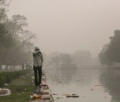 A man walks near a park littered with trash from a festival amid Air Pollution in India.