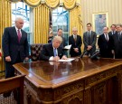 U.S. President Donald Trump signs the first of three Executive Orders in the Oval Office of the White House in Washington, DC on Monday, January 23, 2017