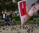 People feed pigeons next to a poster of political party 'Barcelona en Comu' (Barcelona in Common) Leader Ada Colau are seen during a Municipal Elections rally on May 20, 2015 in Barcelona, Spain.