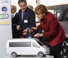 German Chancellor Angela Merkel looks at a plug used for charging an electric car while visitng the EnBW stand at the Electro-Mobility Conference at the Berlin Congress Center on May 27, 2013 in Berli