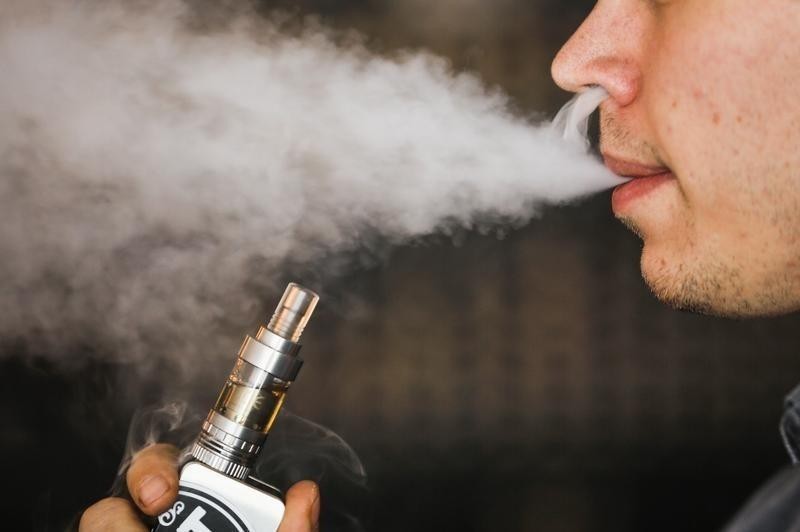 A teenage man using a flavored e-cigarette
