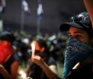 Participants hold lit candles at a gathering in front of the Central Electoral Board to protest on the suspension of nationwide municipal elections due to an electronic glitch only four hours after voting began on last Sunday, in Santo Domingo