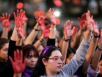 Women raise their hands as they protest against gender violence and femicide in Puebla