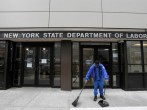 A person sweeps outside the entrance of the New York State Department of Labor offices,