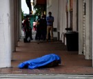 People stand in line outside a shop near the dead body of a man who had collapsed on the sidewalk, during the outbreak of the coronavirus disease (COVID-19), in Guayaquil