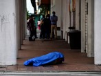 People stand in line outside a shop near the dead body of a man who had collapsed on the sidewalk, during the outbreak of the coronavirus disease (COVID-19), in Guayaquil