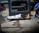 Health workers wearing protective gear bring a dead body past a refrigerated container outside of Teodoro Maldonado Carbo Hospital amid the spread of the coronavirus disease (COVID-19), in Guayaquil