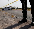 A policeman keeps watch near the wreckage of a car that was burnt in a blockade set by members of the Santa Rosa de Lima Cartel to repel security forces during a police operation on the outskirts of Celaya