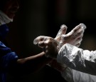 An activist wearing protective suit helps a pedestrian to put on gloves, during an awareness campaign, amid the spread of the coronavirus disease (COVID-19), in Monterrey