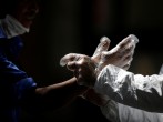 An activist wearing protective suit helps a pedestrian to put on gloves, during an awareness campaign, amid the spread of the coronavirus disease (COVID-19), in Monterrey