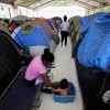 A migrant woman bathes her son outside their tent at a migrant encampment, where more than 2,000 people live while seeking asylum in the U.S, as the spread of the coronavirus disease (COVID-19) continues, in Matamoros