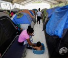 A migrant woman bathes her son outside their tent at a migrant encampment, where more than 2,000 people live while seeking asylum in the U.S, as the spread of the coronavirus disease (COVID-19) continues, in Matamoros