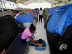 A migrant woman bathes her son outside their tent at a migrant encampment, where more than 2,000 people live while seeking asylum in the U.S, as the spread of the coronavirus disease (COVID-19) continues, in Matamoros