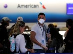 FILE PHOTO: A passenger wearing a mask waits in line to check in for a flight at Miami International Airport