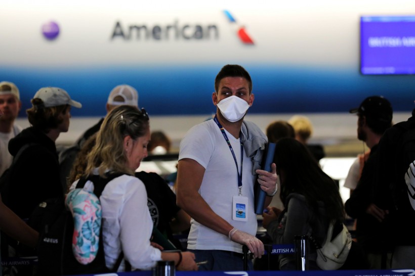 FILE PHOTO: A passenger wearing a mask waits in line to check in for a flight at Miami International Airport