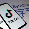 Tik Tok logos are seen on smartphones in front of a displayed ByteDance logo in this illustration.