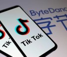 Tik Tok logos are seen on smartphones in front of a displayed ByteDance logo in this illustration.