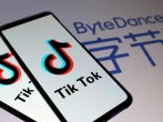 Tik Tok logos are seen on smartphones in front of a displayed ByteDance logo in this illustration.