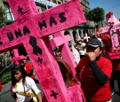 Women carry pink crosses during the 