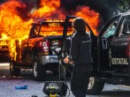 A police officer stands near a burning police vehicle after demonstrators set it on fire during a protest