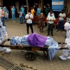 Health workers wearing Personal Protective Equipment (PPE) carry the body of a person who who died due to the coronavirus disease (COVID-19),