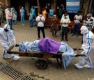 Health workers wearing Personal Protective Equipment (PPE) carry the body of a person who who died due to the coronavirus disease (COVID-19),