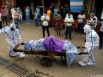 Health workers wearing Personal Protective Equipment (PPE) carry the body of a person who who died due to the coronavirus disease (COVID-19),