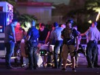  Police officers stand by as medical personnel tend to a person on Tropicana Ave. near Las Vegas Boulevard after a mass shooting