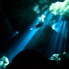 A scuba diver swims through rays of light coming into a massive underground, underwater cave in the Cenote Taj Maha in Quintana Roo, Mexico on September 27, 2018