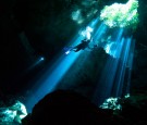 A scuba diver swims through rays of light coming into a massive underground, underwater cave in the Cenote Taj Maha in Quintana Roo, Mexico on September 27, 2018