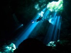 A scuba diver swims through rays of light coming into a massive underground, underwater cave in the Cenote Taj Maha in Quintana Roo, Mexico on September 27, 2018