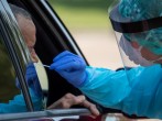 Health care worker uses a swab to test man at COVID-19 drive in testing location in Houston, Texas