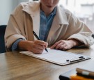 Focused woman writing in clipboard while hiring candidate