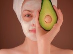 woman with white face mask holding green fruit