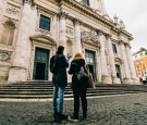 man and woman standing in front of white concrete building during daytime