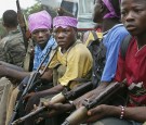  Liberian child soldiers loyal to the government sit silently before charging at a strategic bridge position July 20, 2003 in Monrovia, Liberia